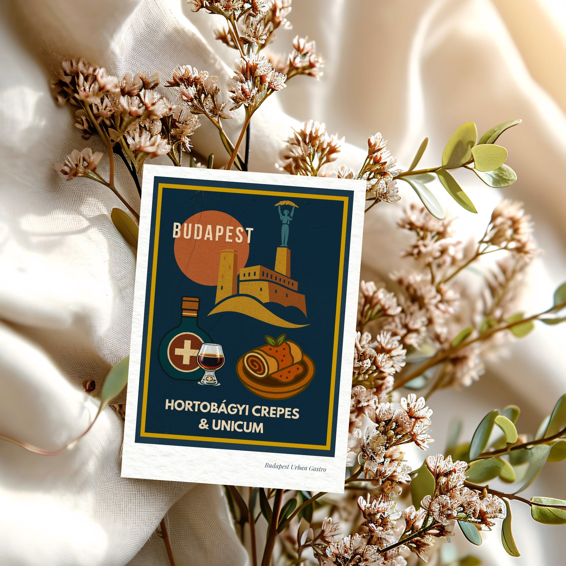 Navy blue Budapest Urban Gastro postcard with Hortobágyi crepes and Unicum, styled with delicate dried flowers on a soft textile background in warm European light.