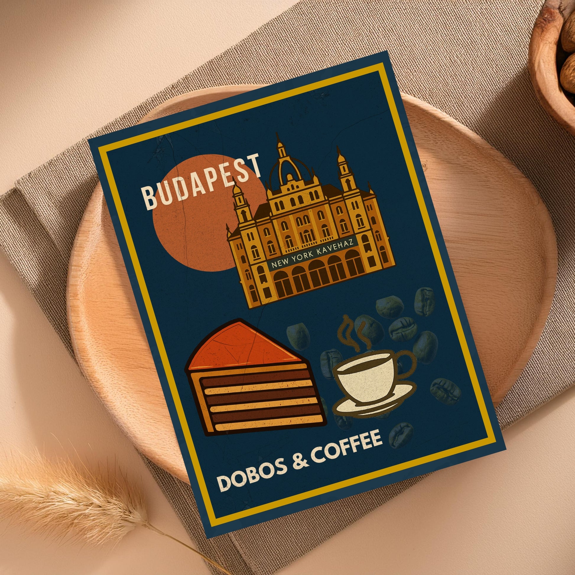 Dobos & Coffee Budapest art print flatlay mockup on wooden table, featuring illustrated Dobos cake, coffee cup and New York Café building in vintage Hungarian gastro style